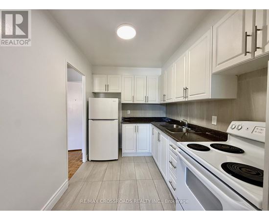 A kitchen with white cabinets and a white fridge.