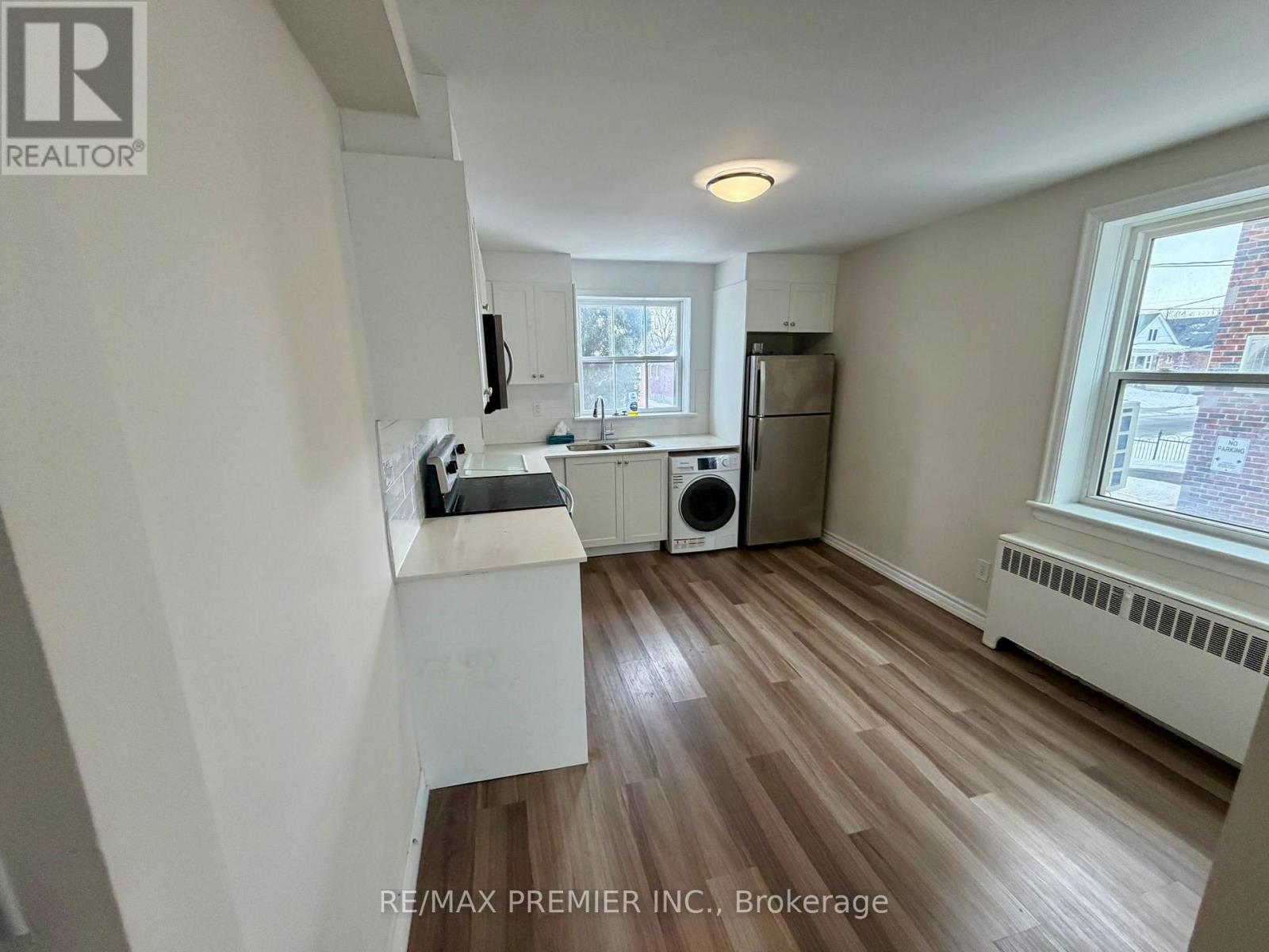 A kitchen with white cabinets and a wooden floor.