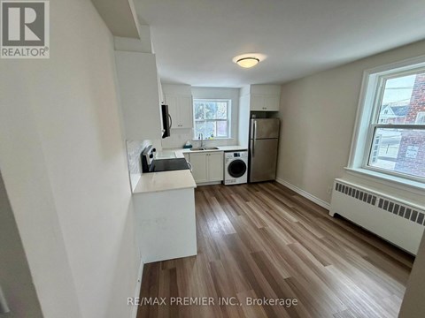 A kitchen with white cabinets and a wooden floor.