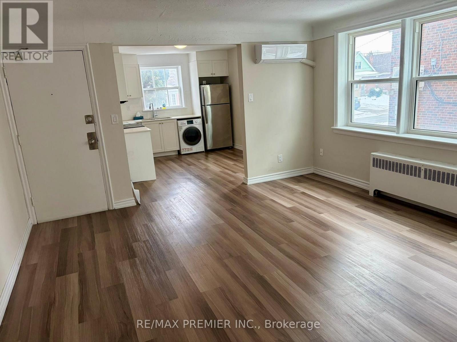A room with wooden flooring and a window with a view of a red building outside.