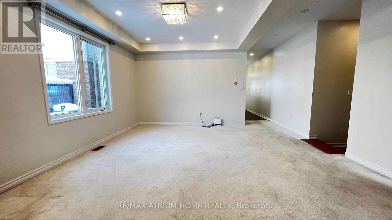 A spacious room with a window and a carpeted floor.