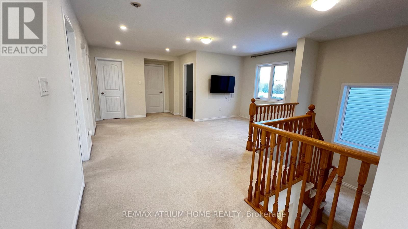 A spacious living room with a television and a wooden staircase.