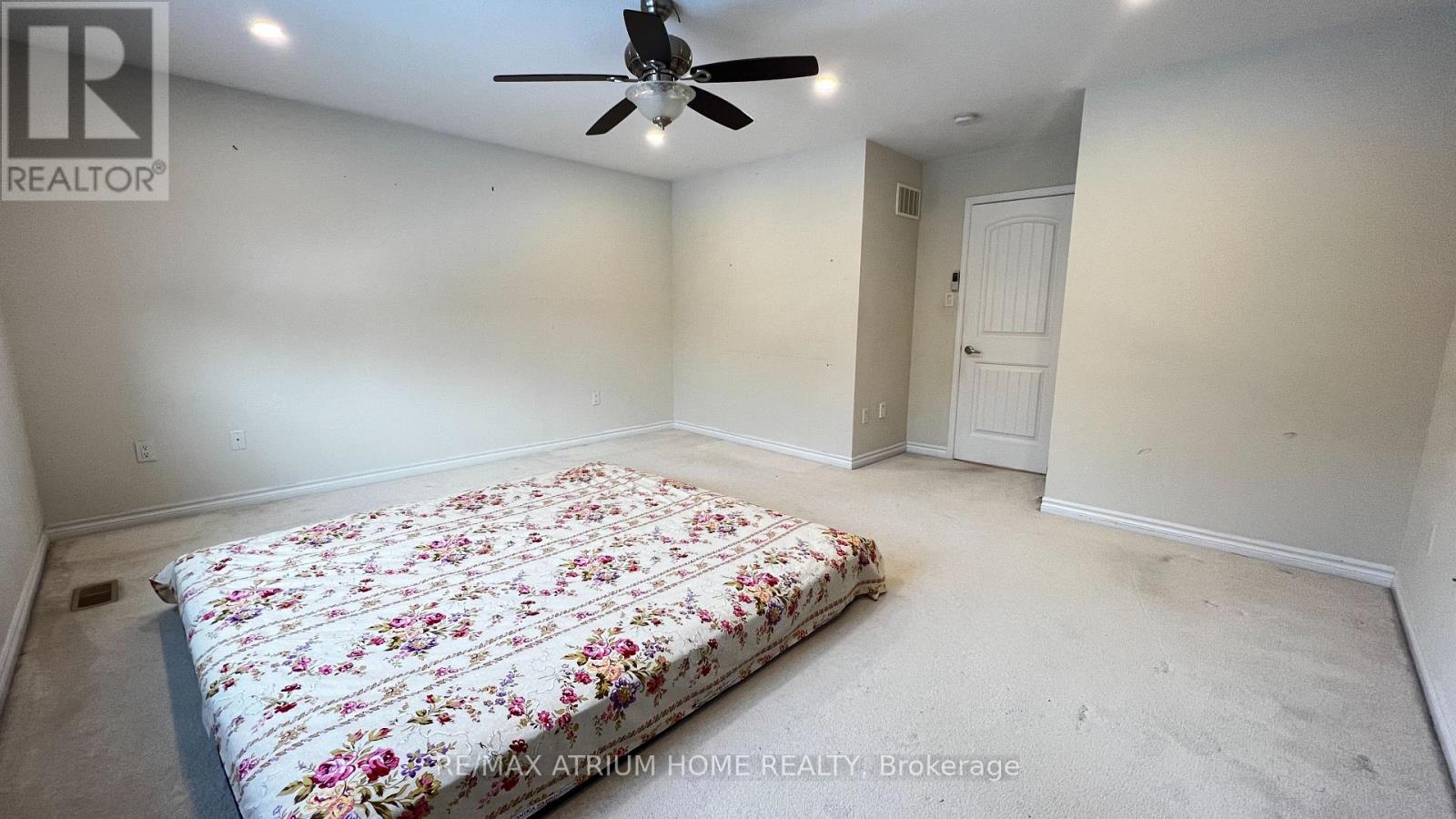 A bedroom with a floral bedspread and a ceiling fan.