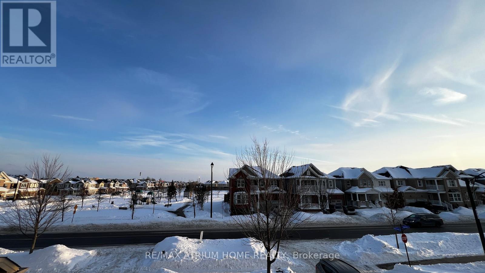 A snowy residential neighborhood with houses and bare trees.