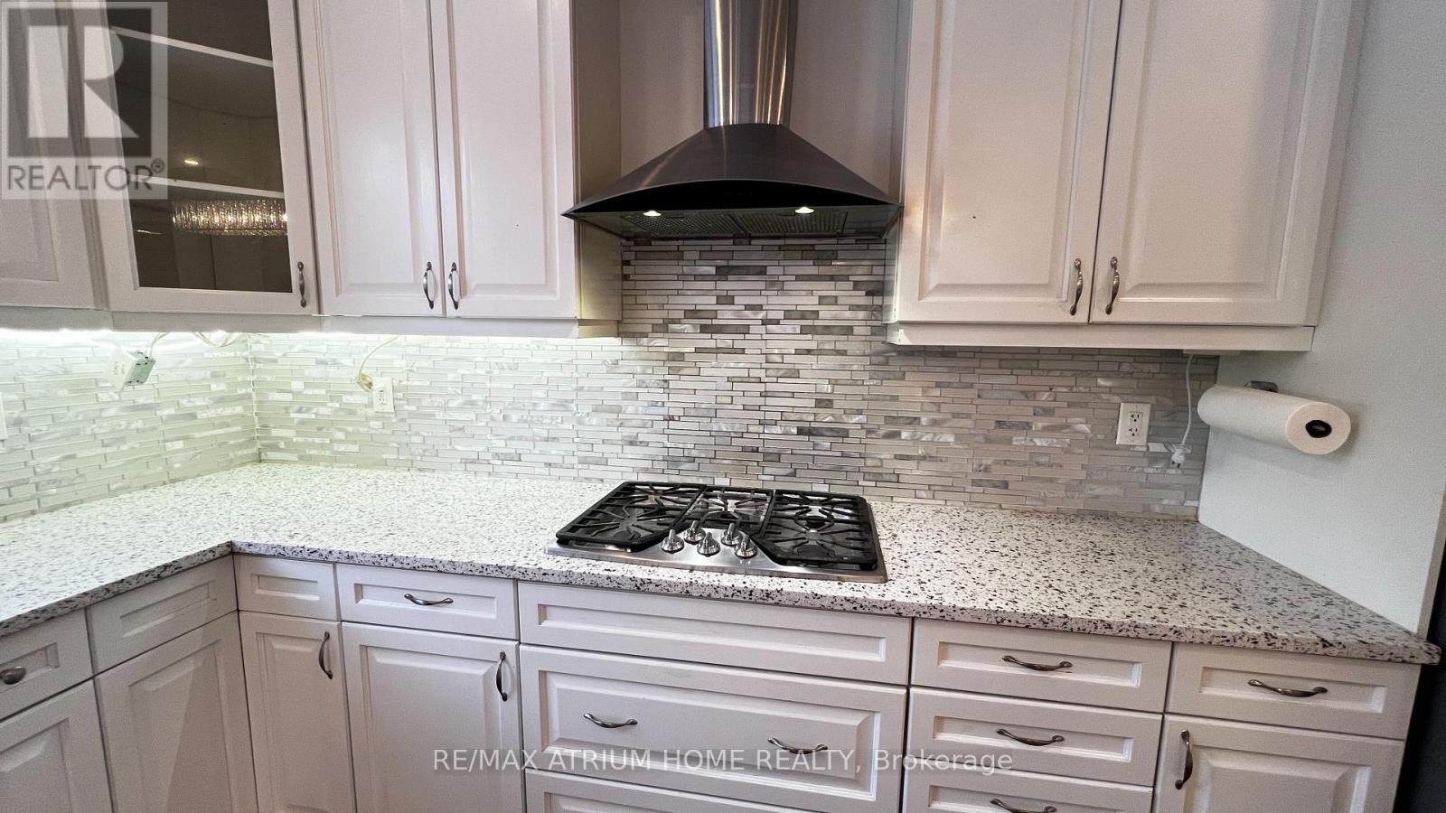 A kitchen with white cabinets and a stone backsplash.