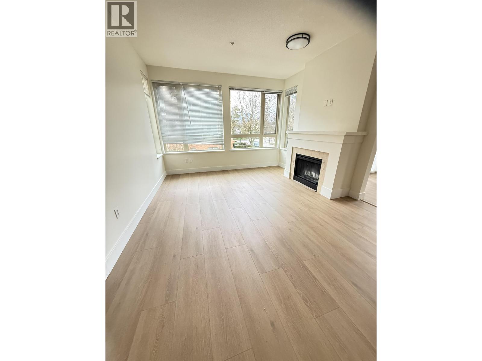 A large, empty room with a fireplace and a window.