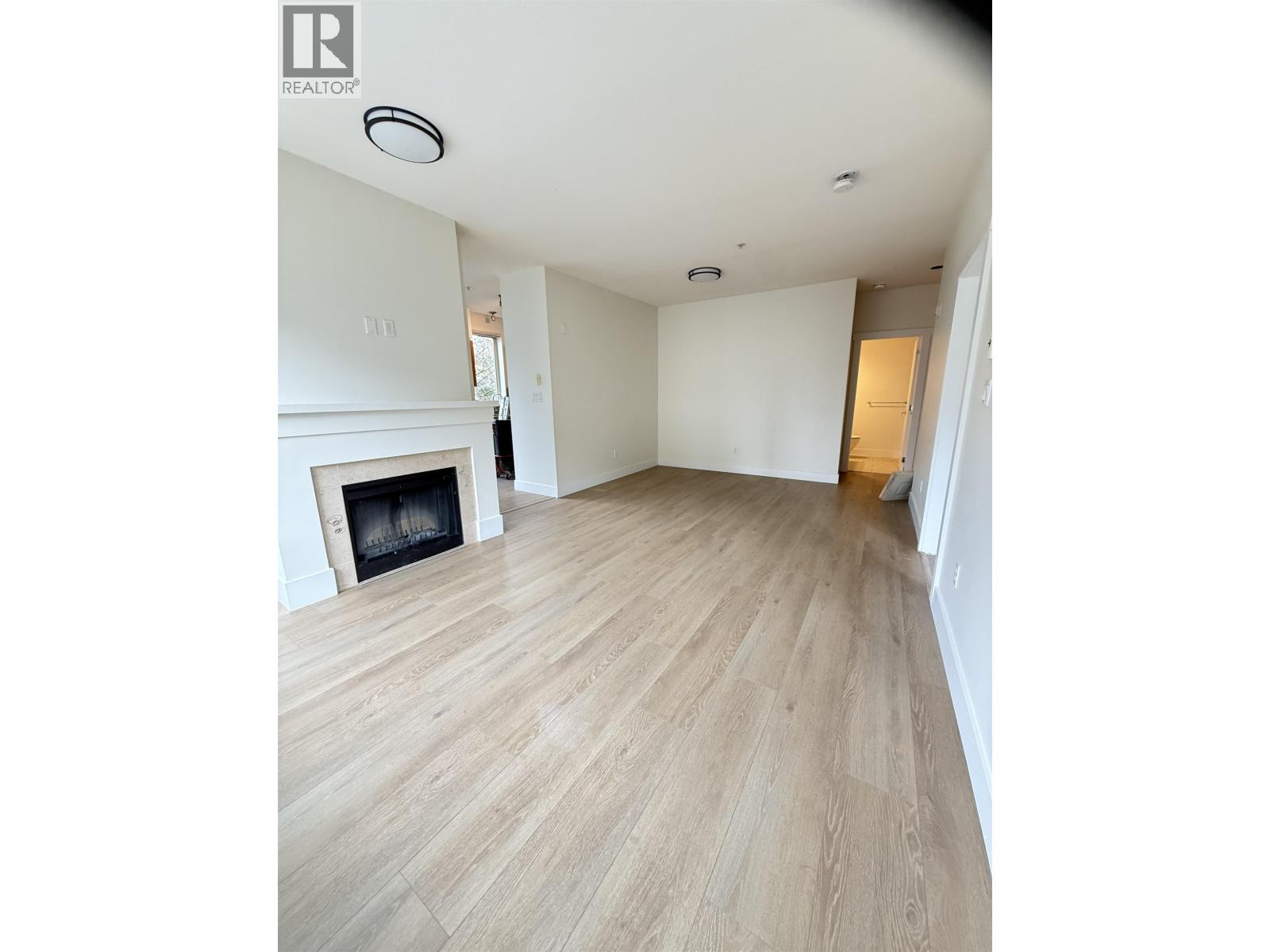 A living room with a fireplace and wood flooring.