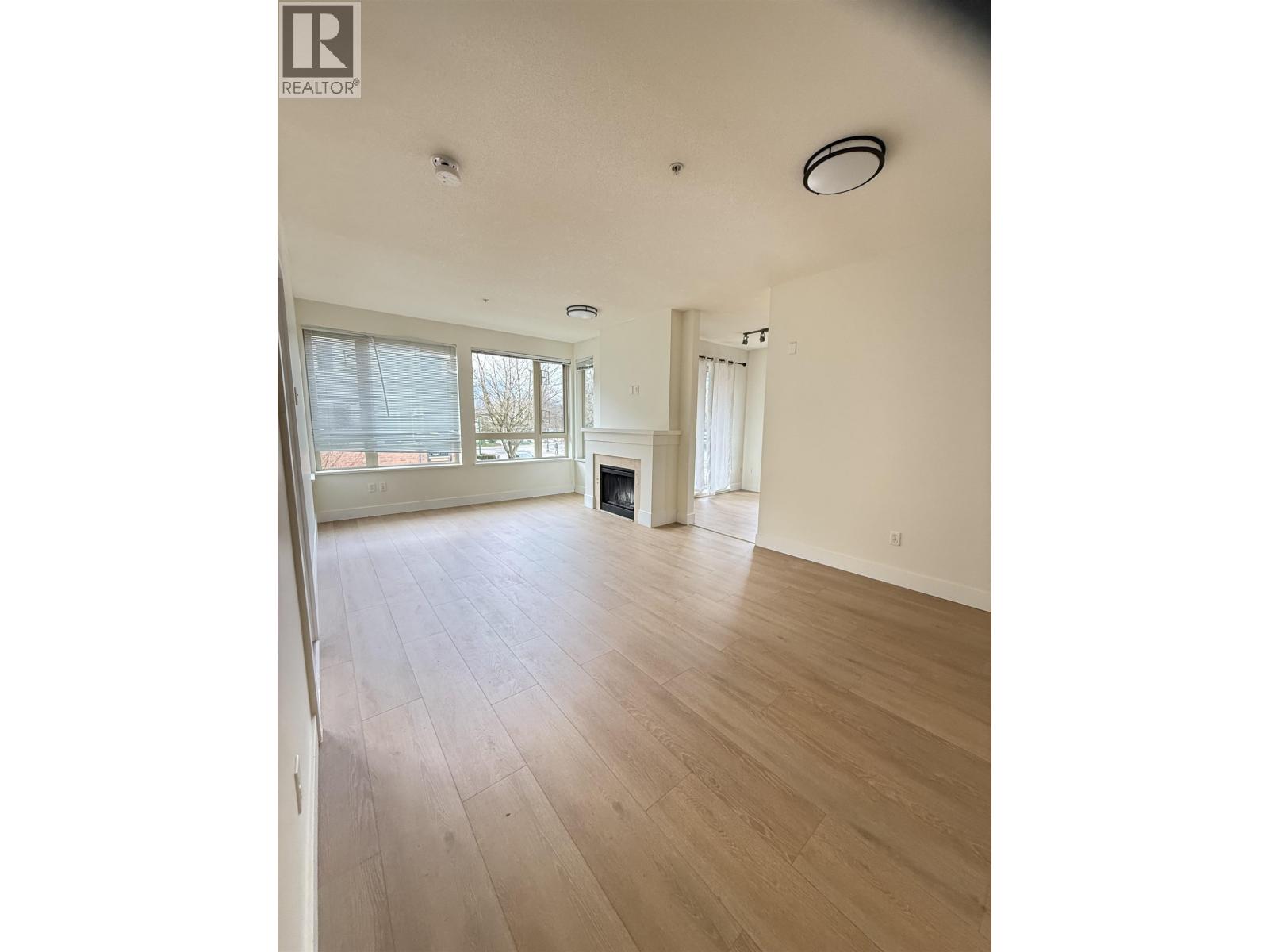 A spacious room with wooden flooring and a large window.