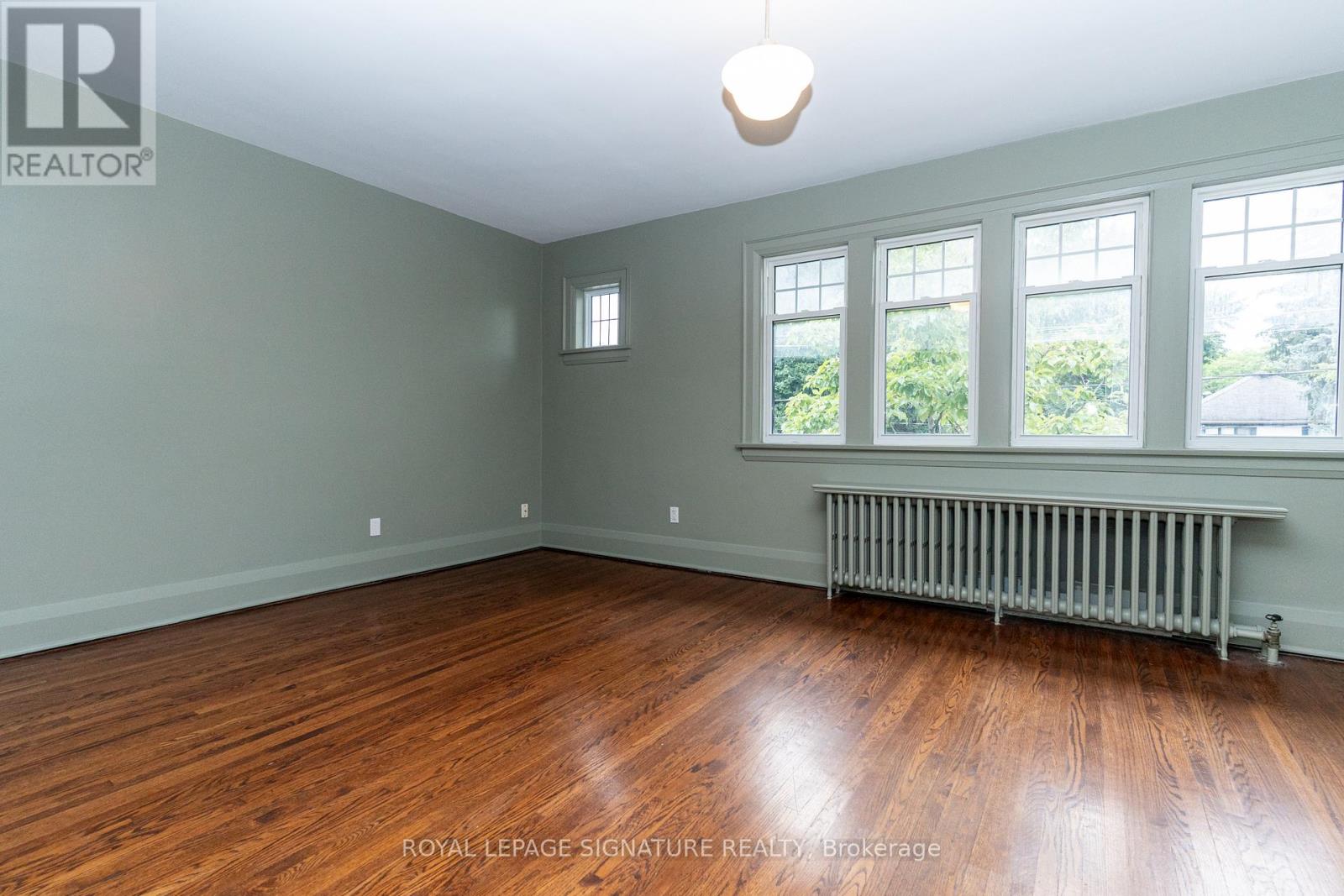 A room with wooden floors and a window with a view of trees.