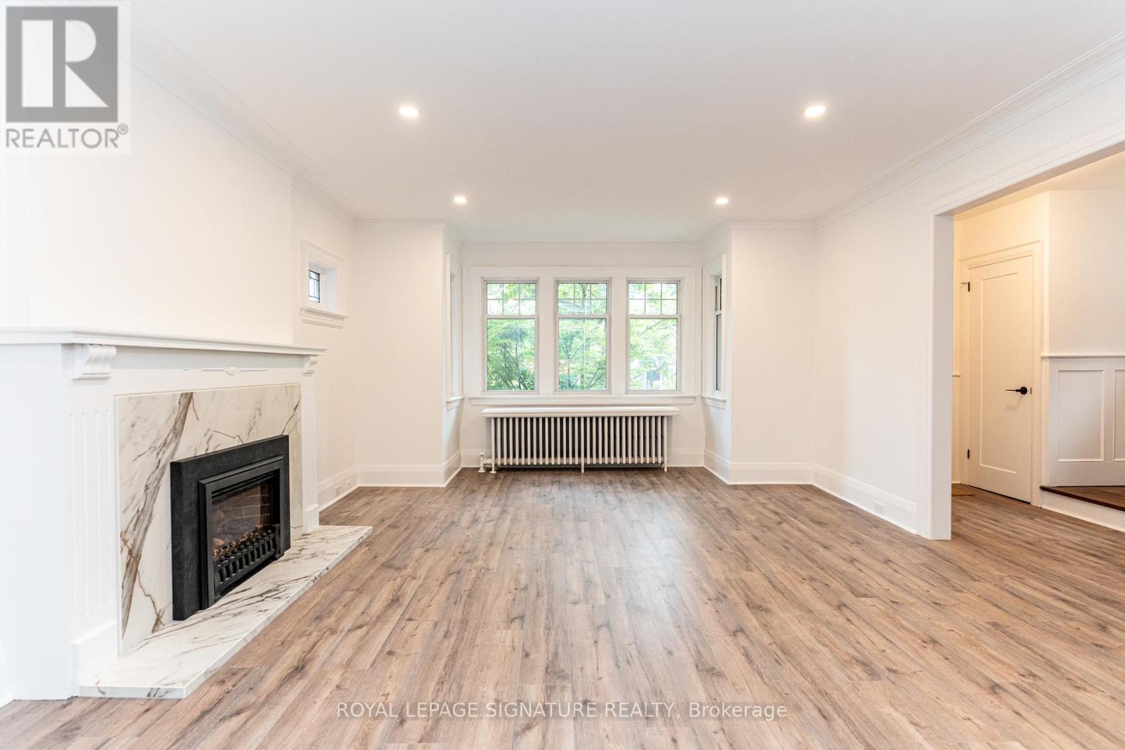 A spacious room with a fireplace and wooden flooring.
