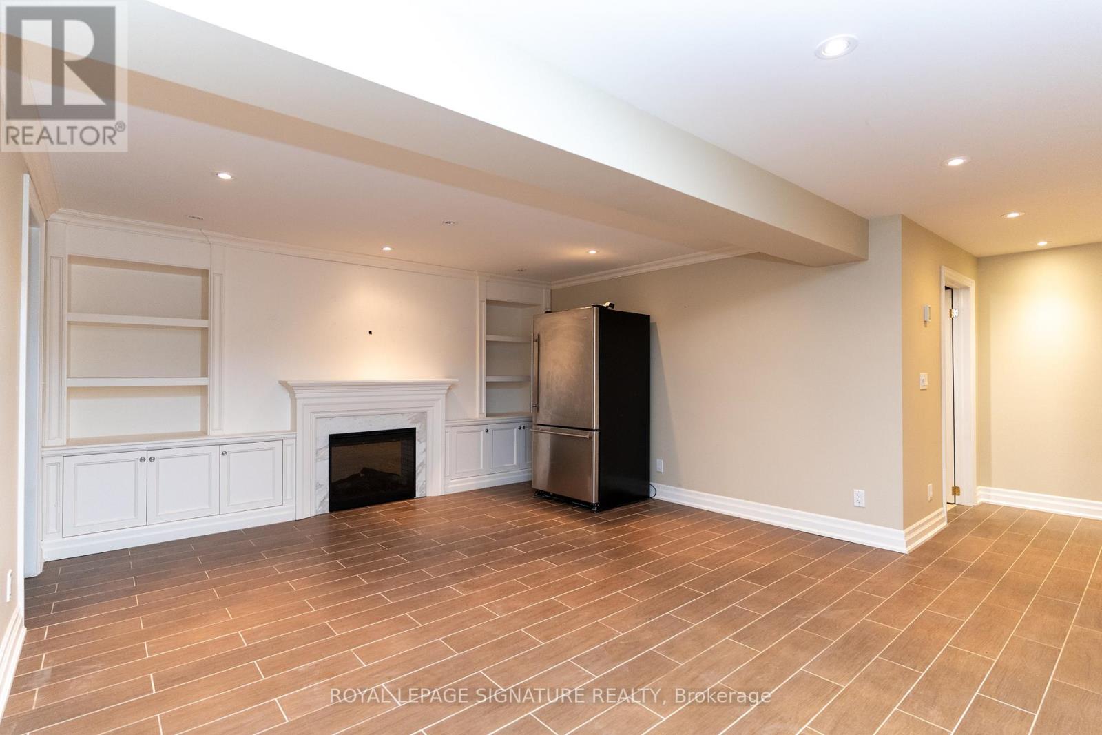 A spacious living room with a fireplace and a refrigerator.