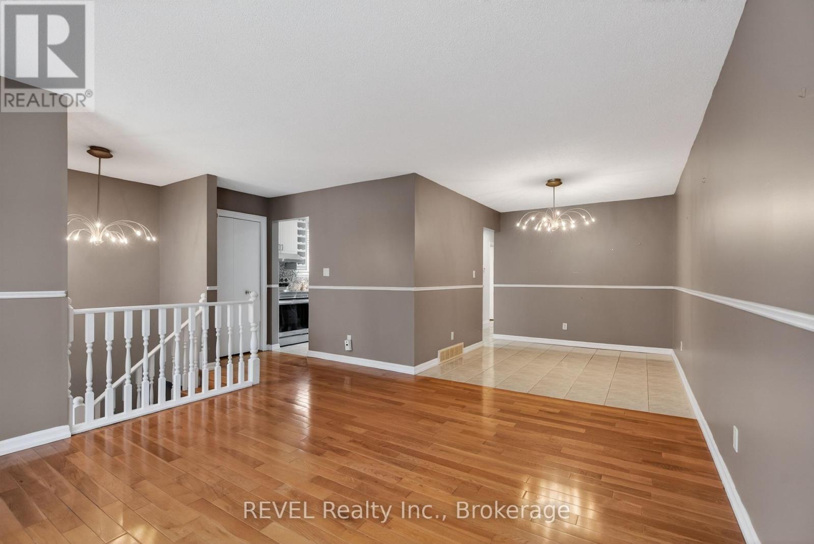A spacious room with wood flooring and white railings.