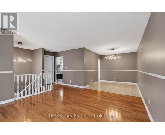 A spacious room with wood flooring and white railings.