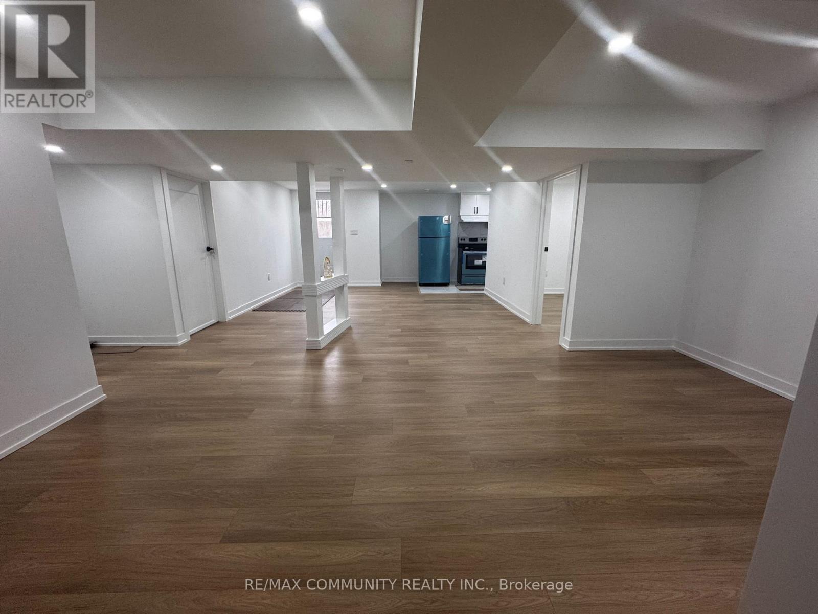 A spacious room with wooden flooring and white walls, with a blue cabinet in the corner.