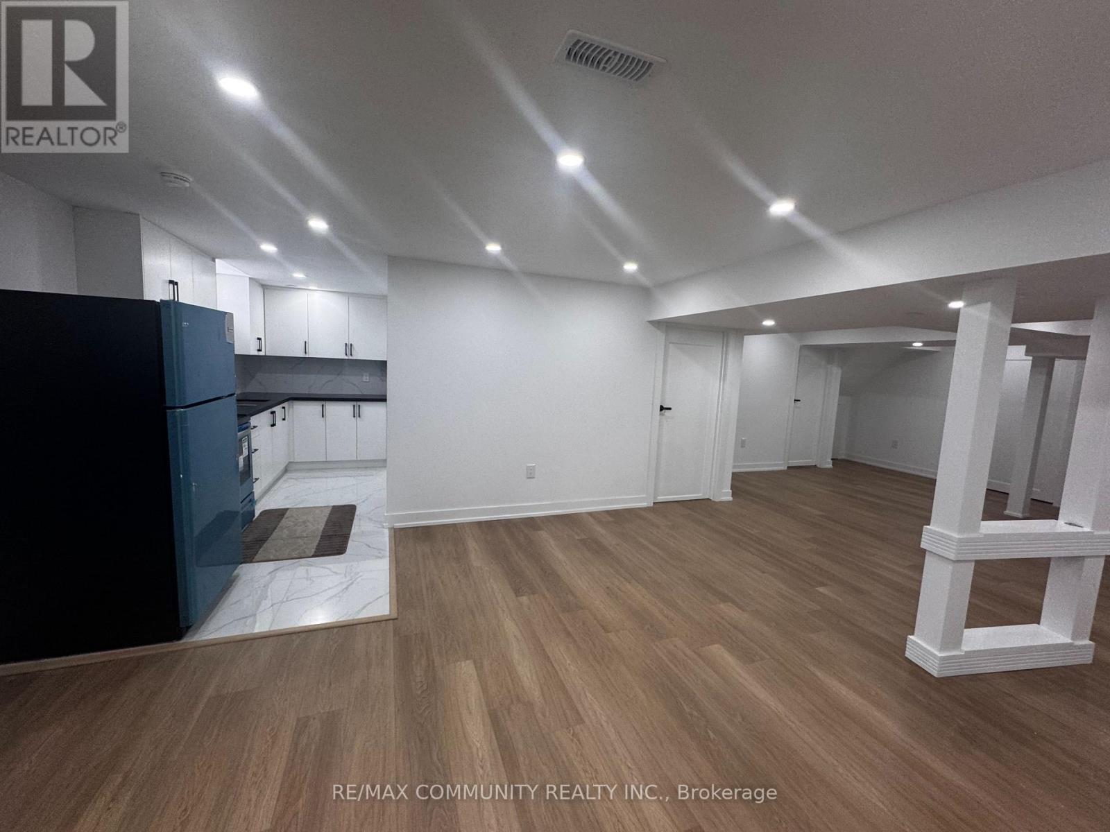 A spacious room with wooden flooring and white walls.