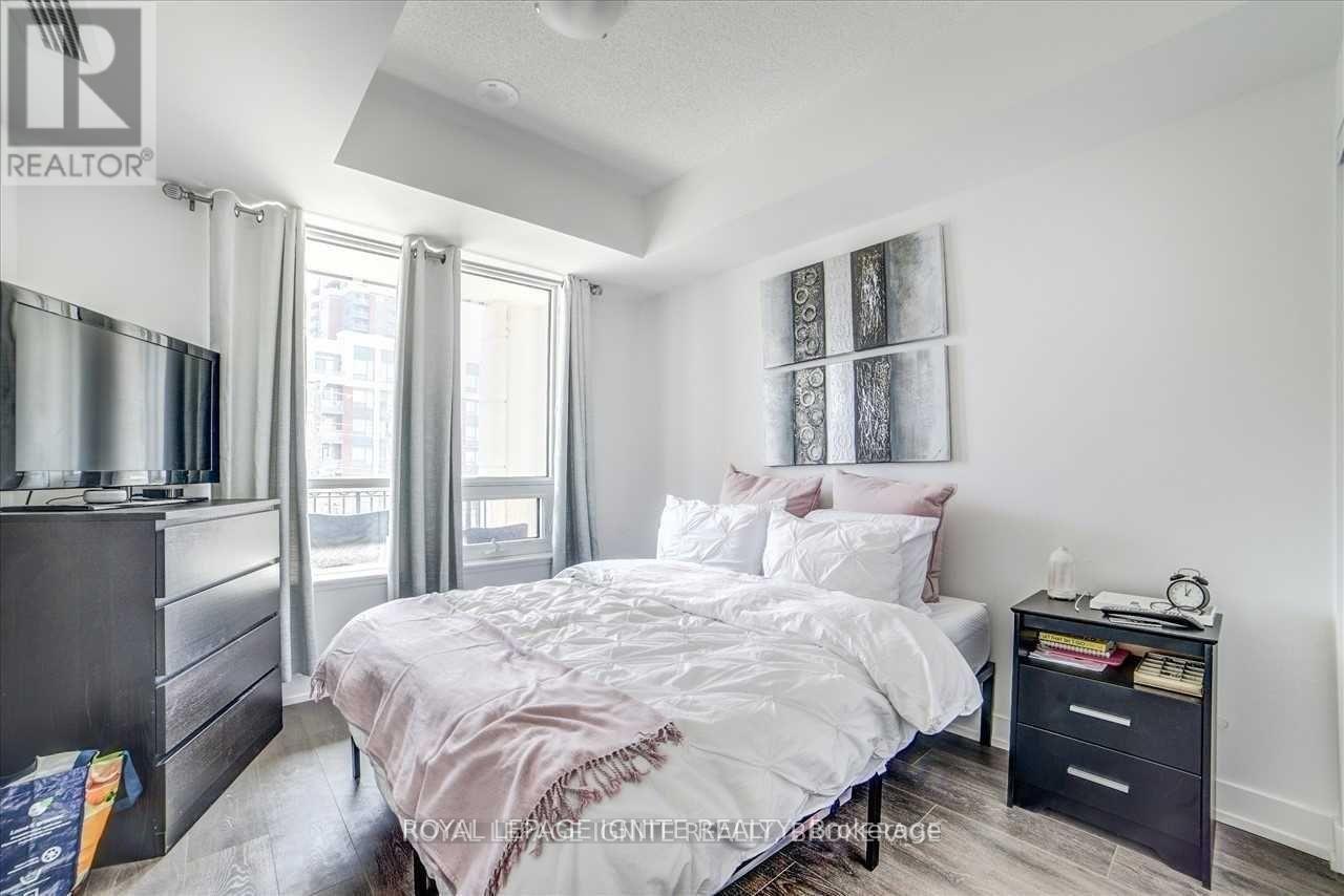 A bedroom with a bed, nightstand, and window.