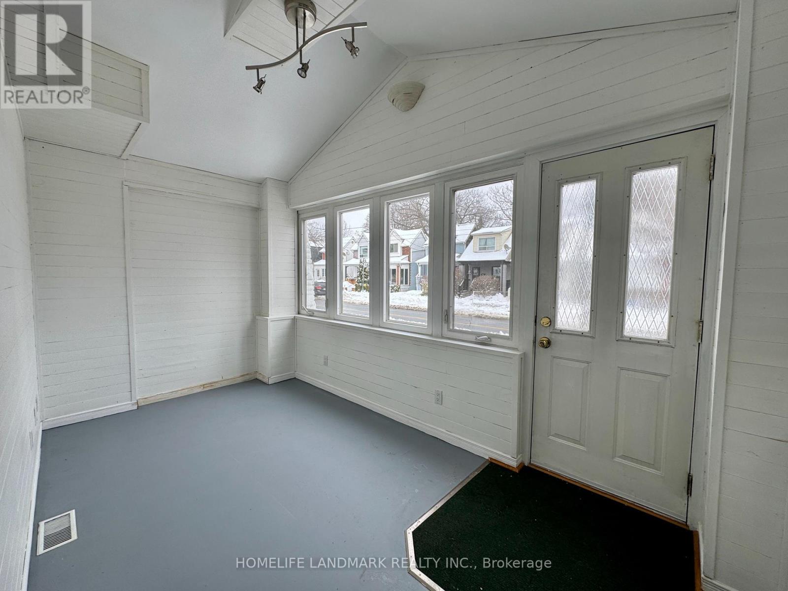 A room with white walls and a door leading to a balcony.