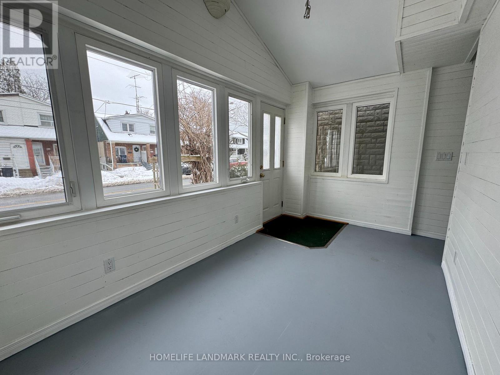 A sunny day at a house with a white siding and a green mat on the floor.