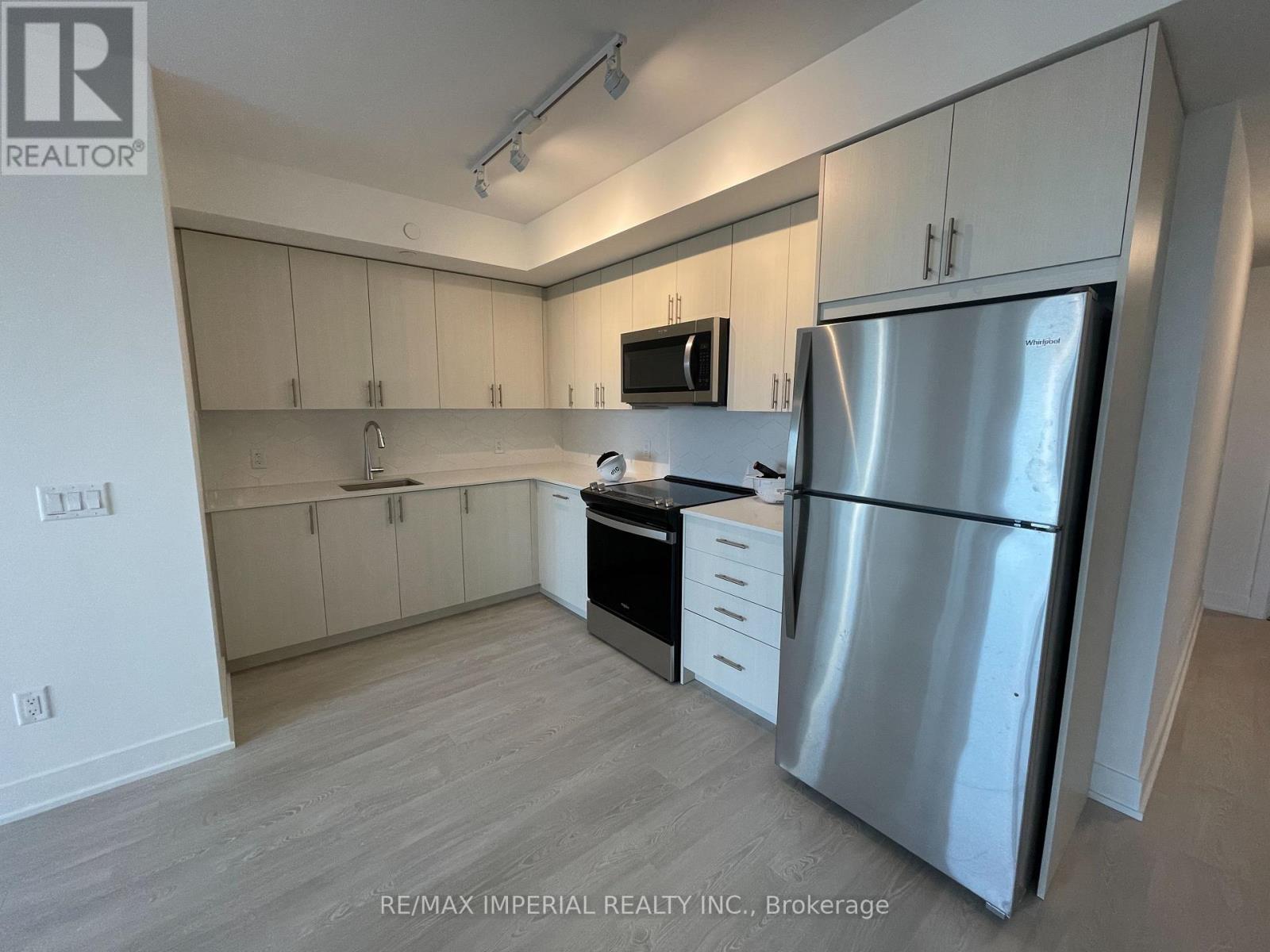 A kitchen with a refrigerator, microwave, and oven.