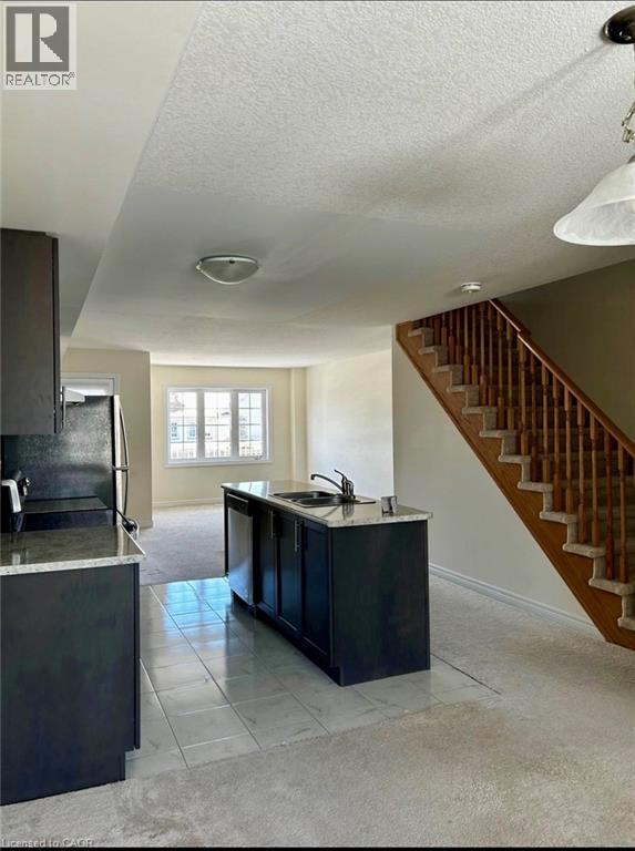 A kitchen with a black island and a staircase in the background.