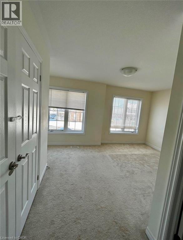 A room with a carpeted floor and two windows.