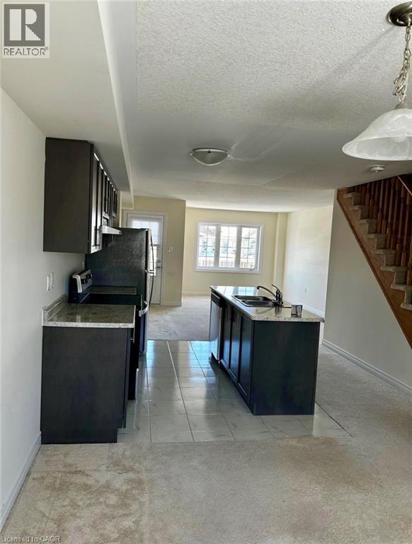 A kitchen with a black countertop and a stainless steel refrigerator.