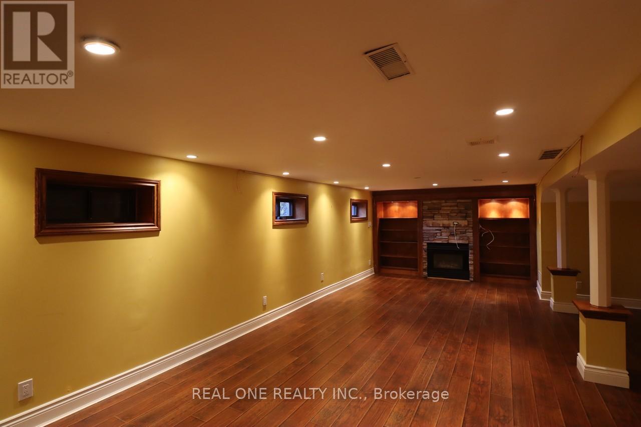 A spacious room with wood flooring and a fireplace.