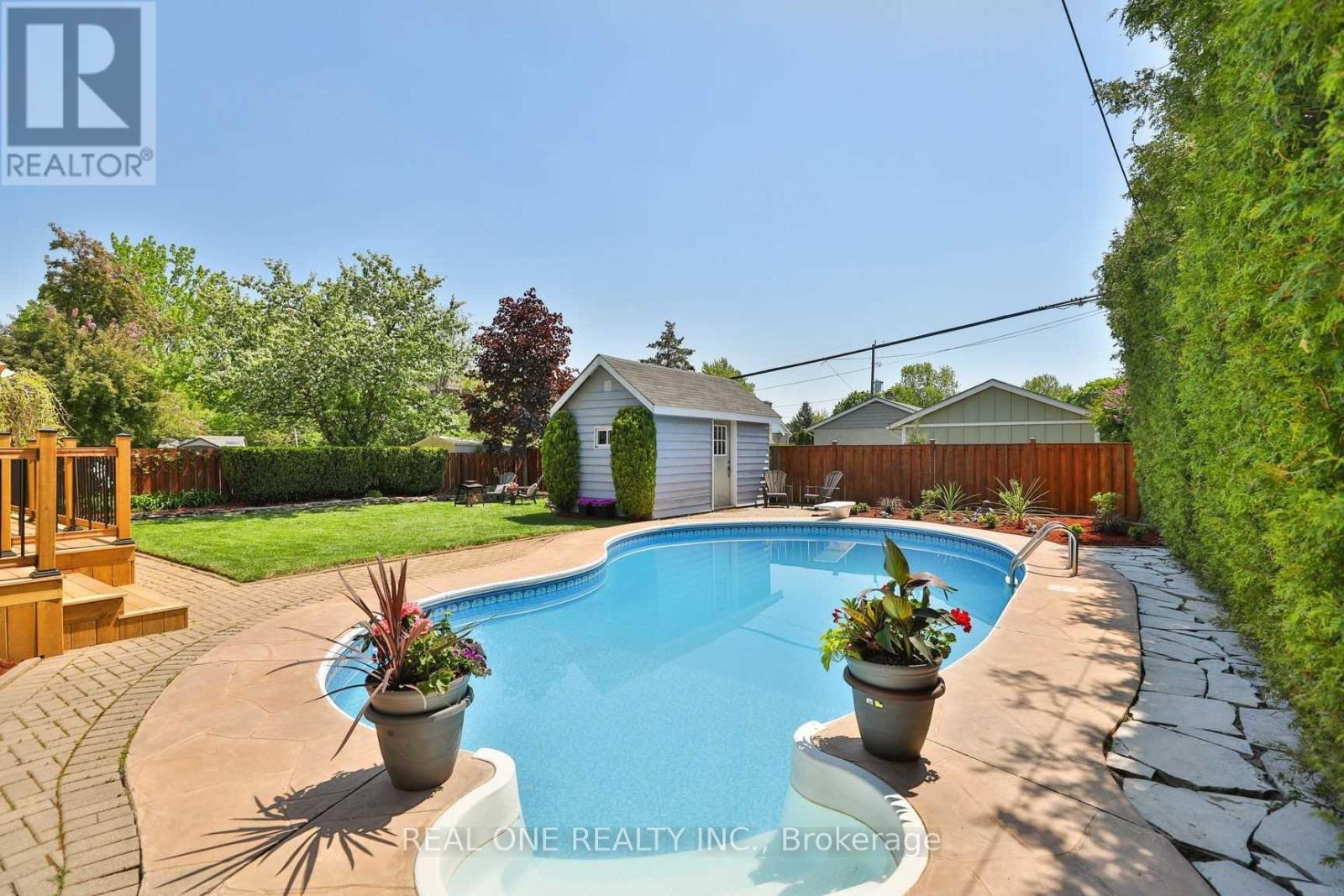 A pool surrounded by a stone path and potted plants.