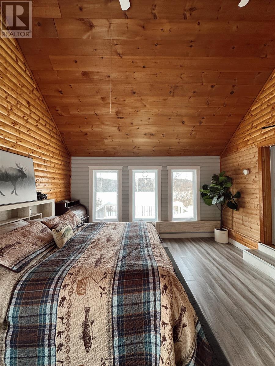 A bedroom with a large bed and wooden walls.