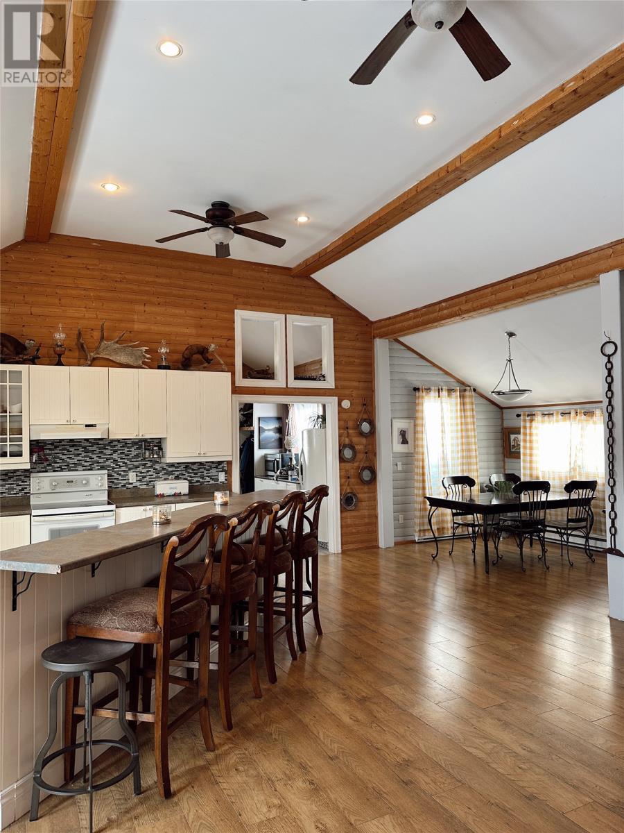 A kitchen with wooden floors and ceiling, a bar area with stools, and a dining area with a table and chairs.