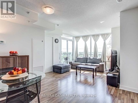 A living room with a glass table and a grey couch.