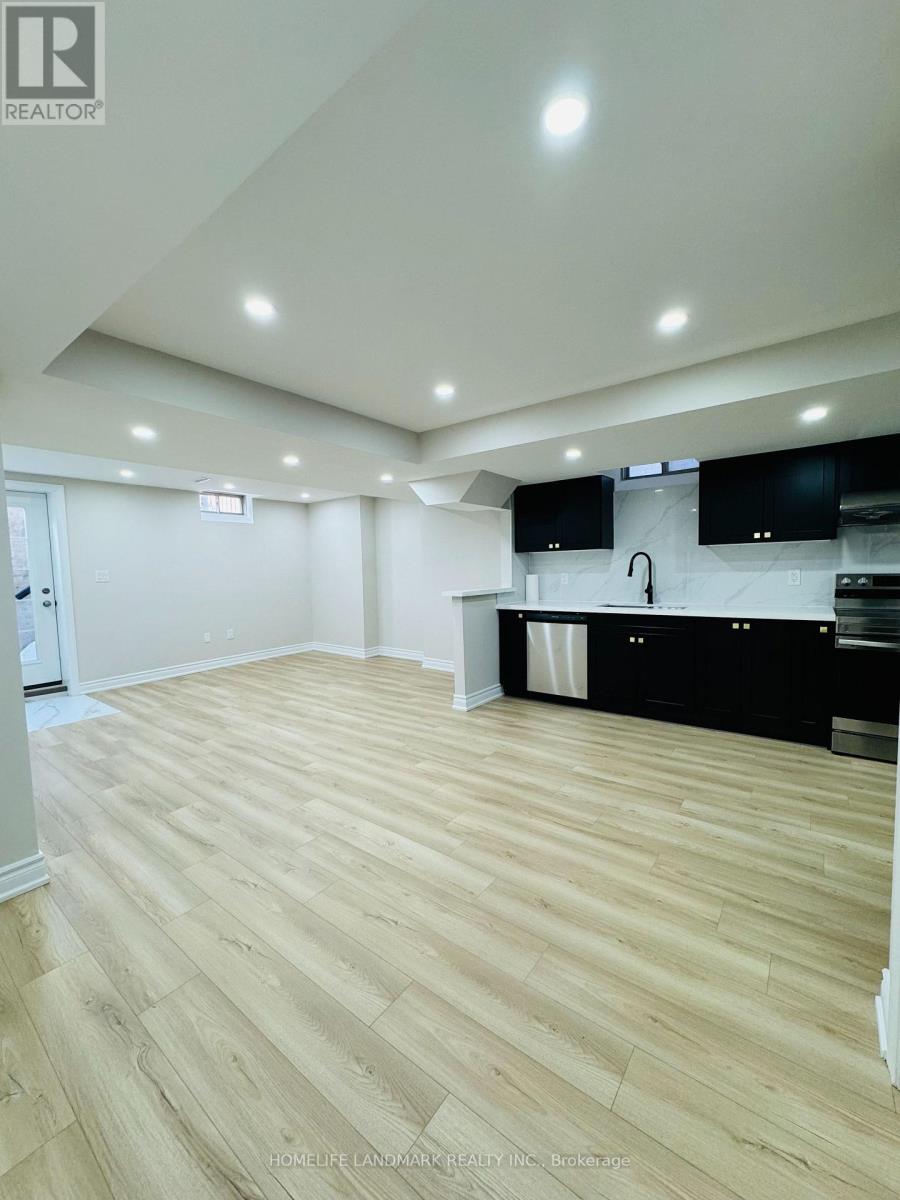 A spacious kitchen with wooden flooring and black cabinets.