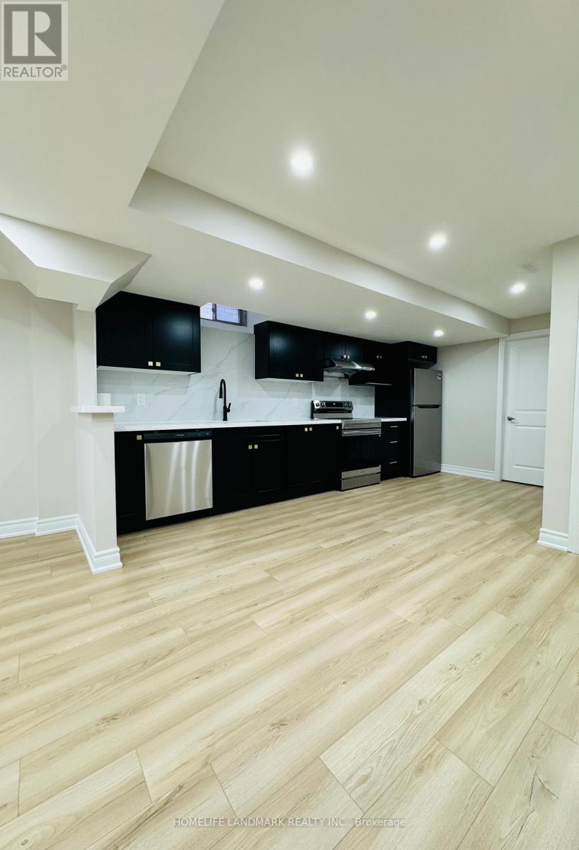 A modern kitchen with wooden floors and black appliances.