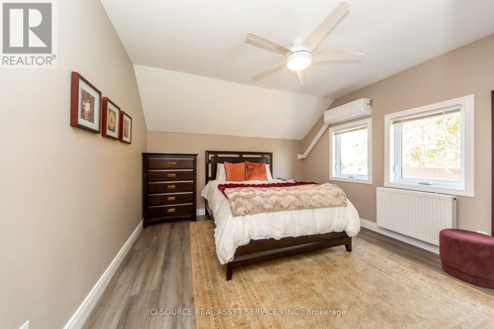 A bedroom with a bed, dresser, and ceiling fan.