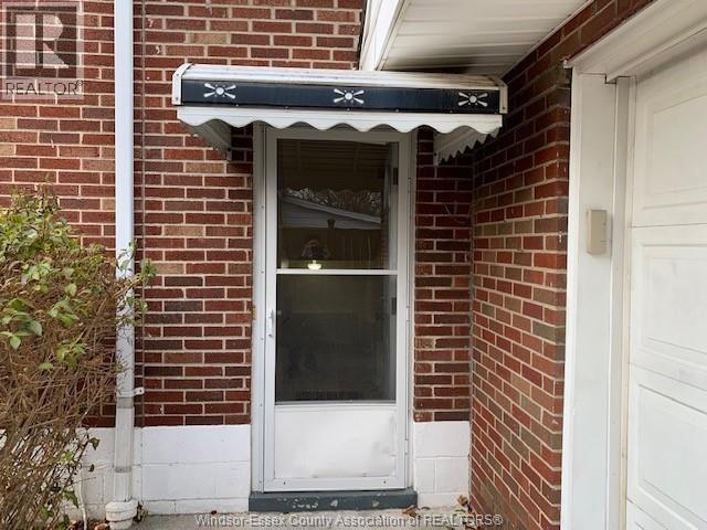 A white door with a window above it is on a brick building.
