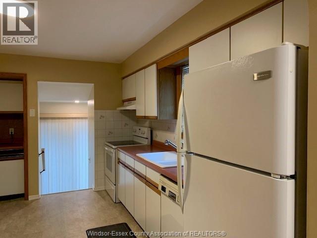 A kitchen with a white refrigerator and wooden cabinets.