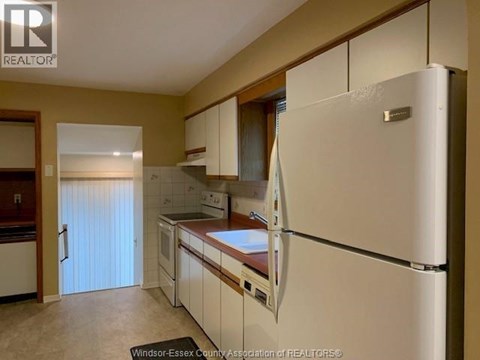 A kitchen with a white refrigerator and wooden cabinets.