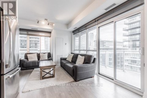 A modern living room with a grey couch and a large window.