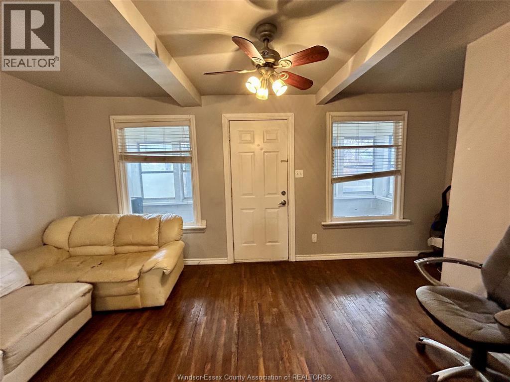 A living room with a beige couch and a ceiling fan.