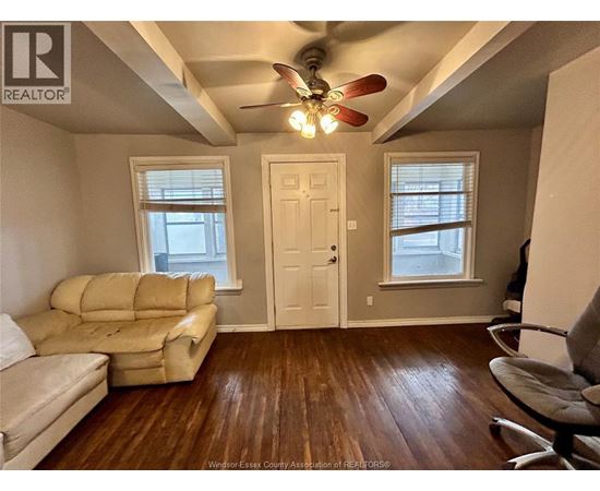 A living room with a beige couch and a ceiling fan.