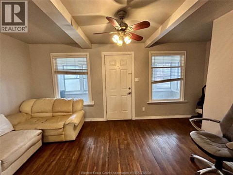 A living room with a beige couch and a ceiling fan.