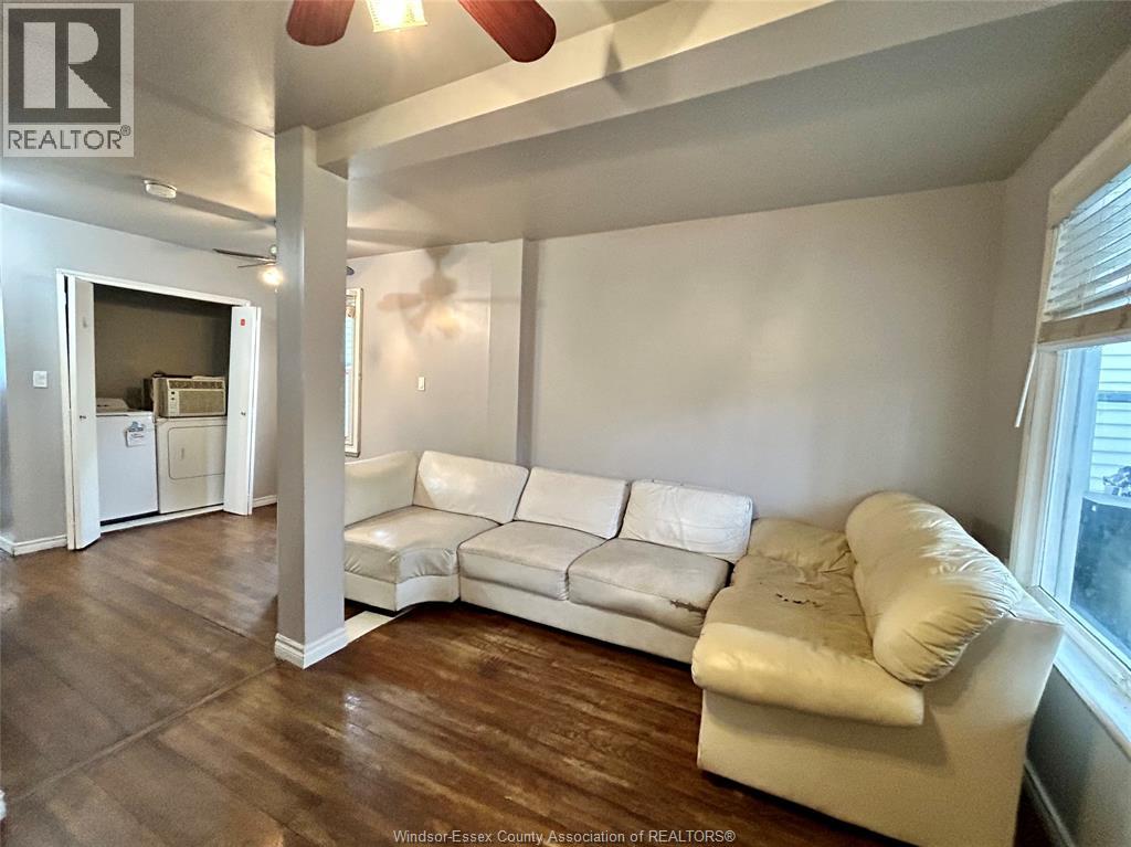 A white couch sits in a room with wood floors and a ceiling fan.