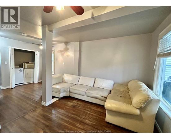 A white couch sits in a room with wood floors and a ceiling fan.