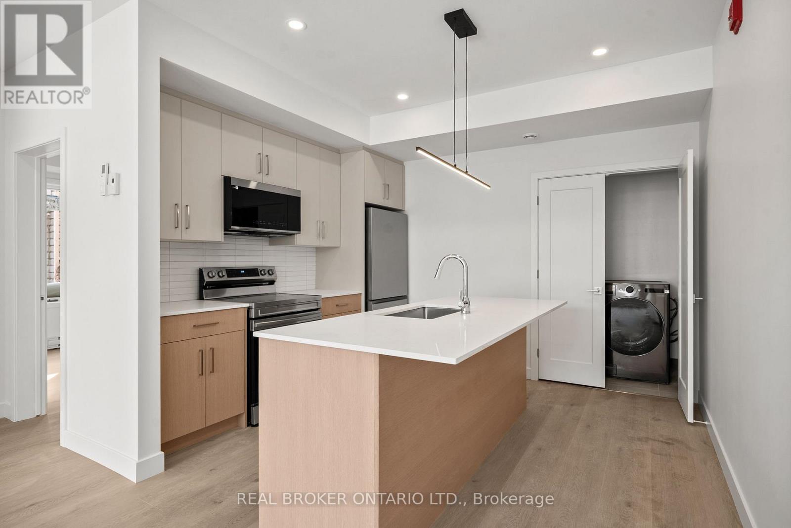 A modern kitchen with a large island and a washing machine tucked away in the corner.