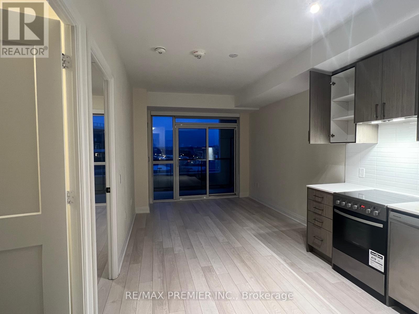 A modern kitchen with a stainless steel oven and a view of the city at night through the window.