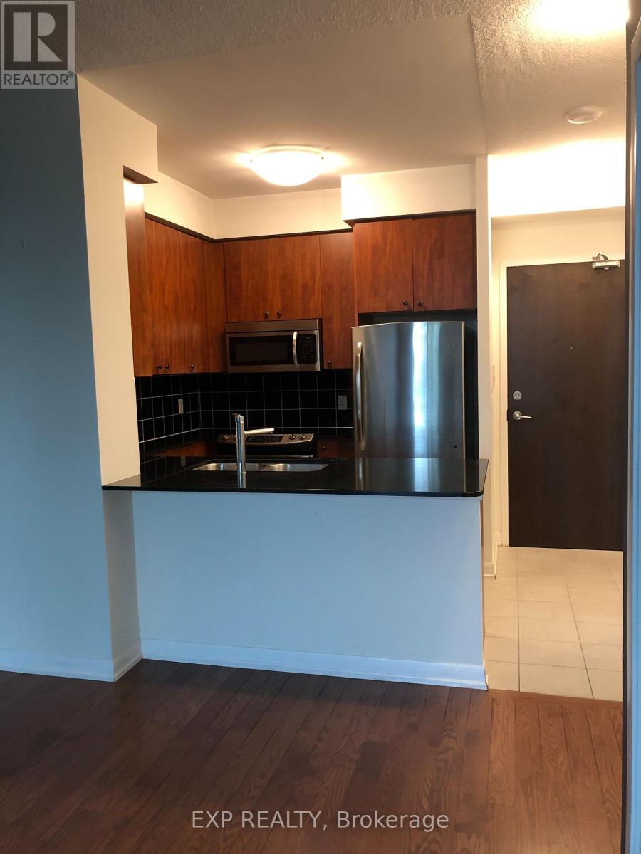 A kitchen with wooden cabinets and a stainless steel refrigerator.