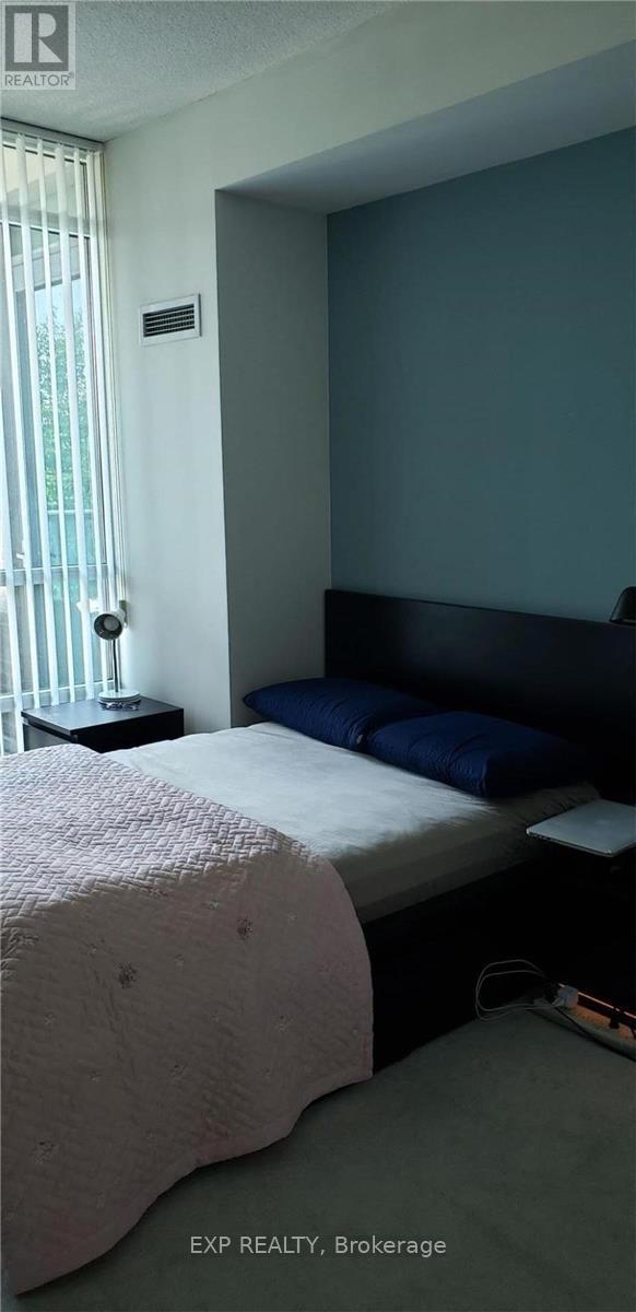 A bedroom with a bed, nightstand, and window.
