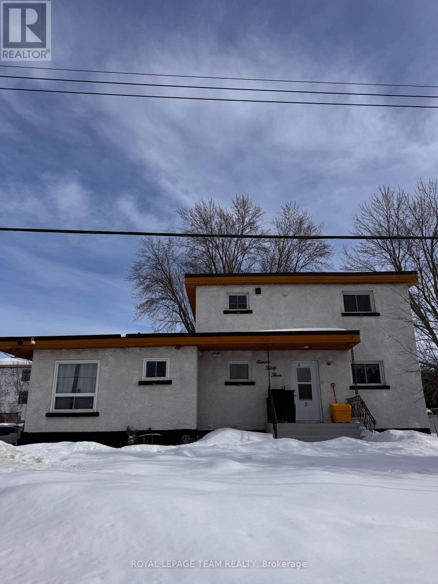 A house with a brown roof and a white wall is surrounded by snow.