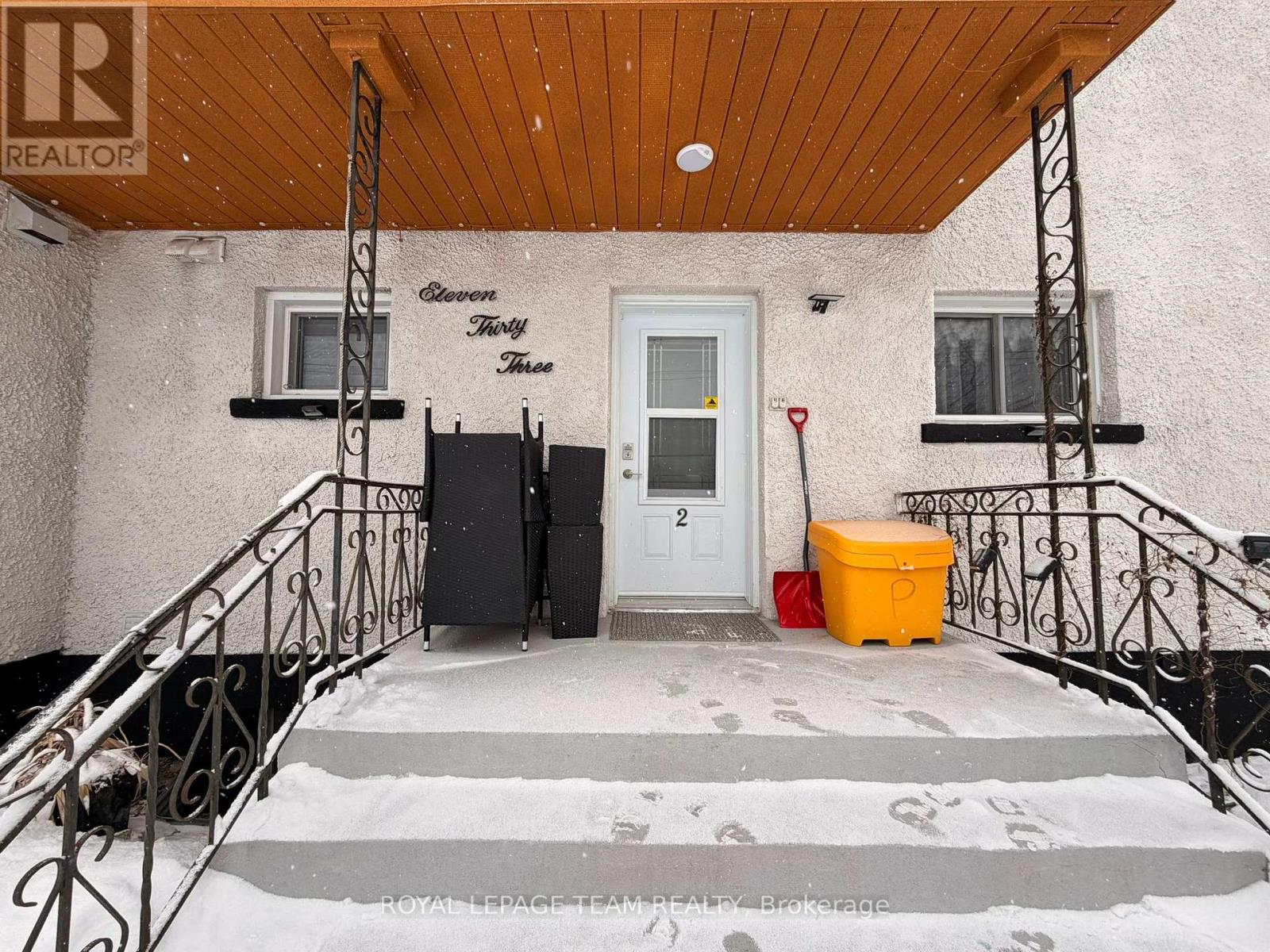 A snow-covered walkway leads to a two-story house with a brown roof.