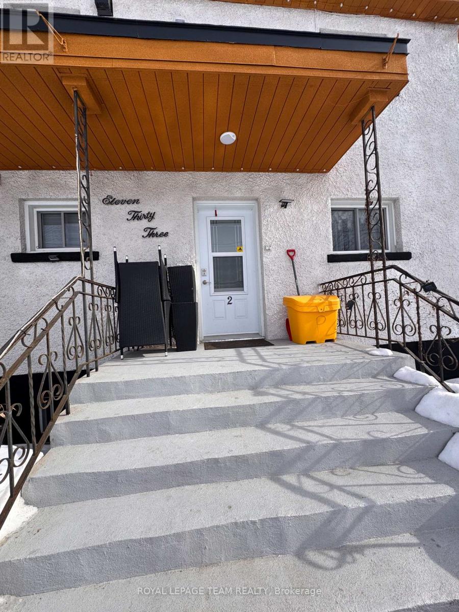 A white house with a black door and a yellow trash can.